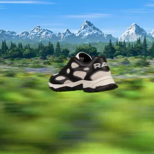 Black and cream RAVI sneaker flying low over a blurred green meadow toward snowy mountains