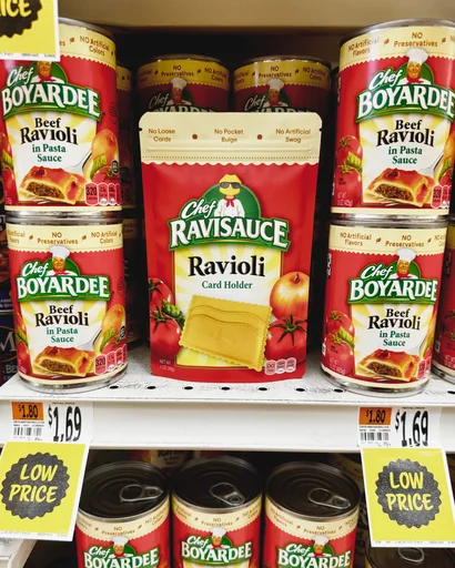 Chef Ravisauce Ravioli Card Holder pouch on a supermarket shelf between cans of Chef Boyardee ravioli
