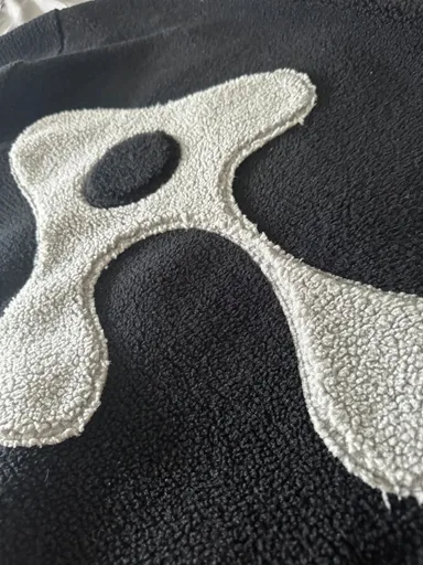 ravisauce mascot white sherpa patch on dark hoodie textile close up alt